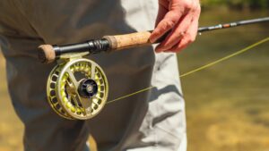 an angler holding a fly fishing rod in the river